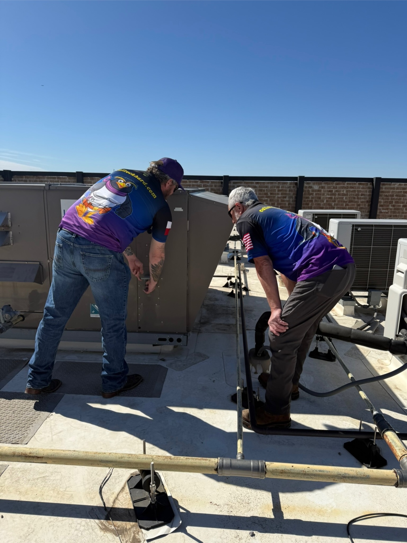 Two Rock Hard technicians inspecting commercial rooftop package unit