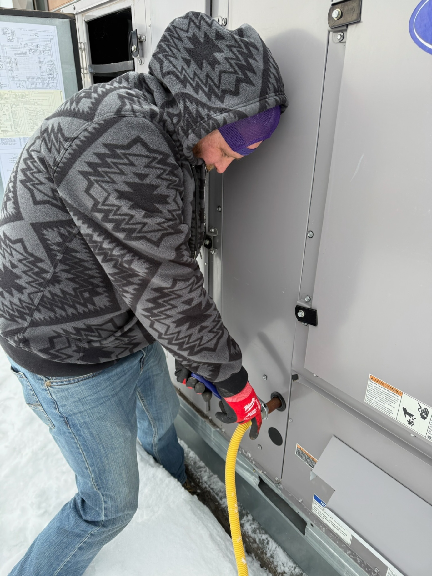 Rock Hard technician actively servicing commercial Carrier condenser during North Texas winter — close-up of heating system maintenance
