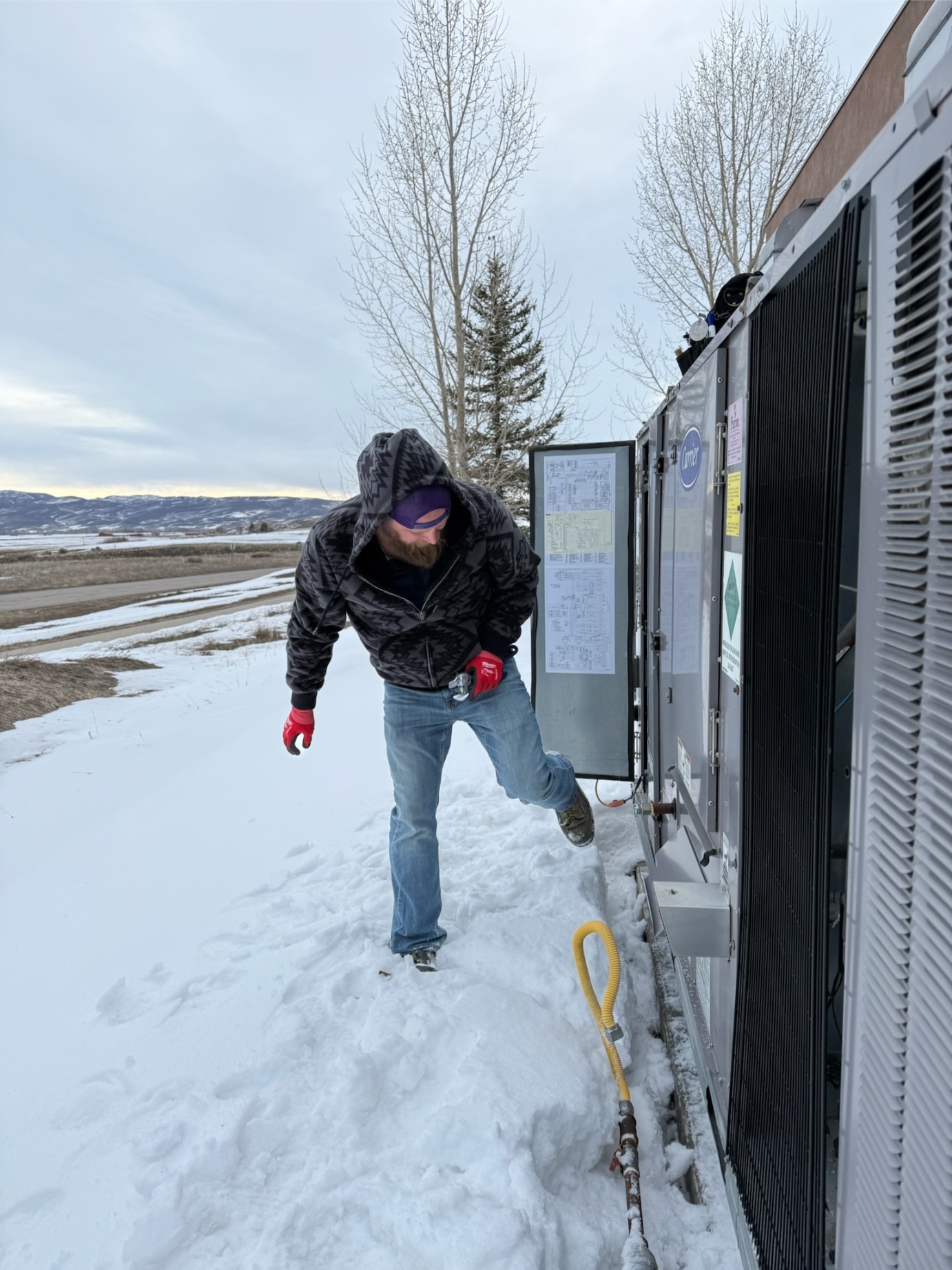 Rock Hard technician inspecting commercial Carrier condenser during winter heating service call